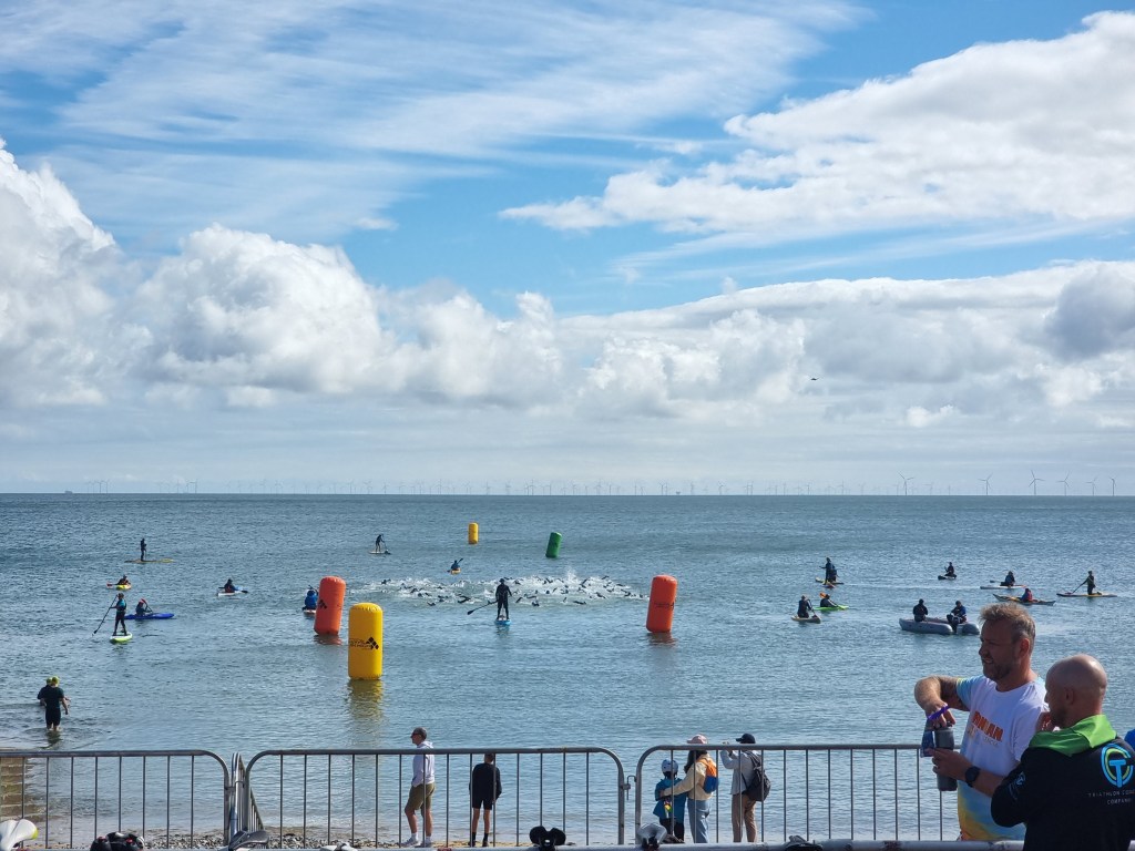 Triathlon participants entering the water at the start of the swim leg in the Llandudno event.