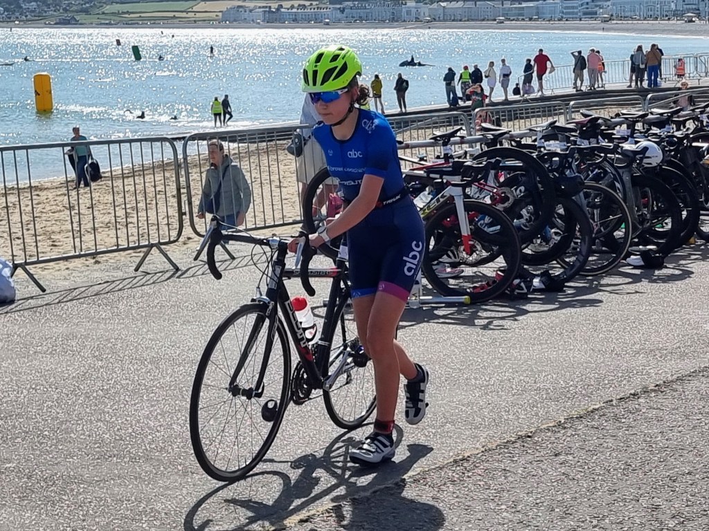 Triathletes in transition area after the swim, removing gear and preparing for the cycling stage in the Llandudno triathlon.
