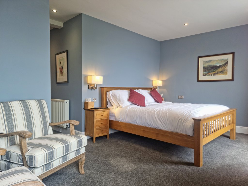Newly refurbished Room 103 in Llandudno featuring a super king bed, comfortable seating area and artwork by William Selwyn.