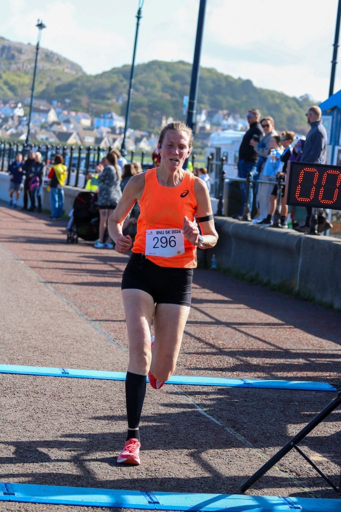 Teresa crosses the finish line at the RNLI Fun Run in Llandudno, completing her first-ever timed 5K race and setting a new personal best of 24 minutes and 40 seconds.