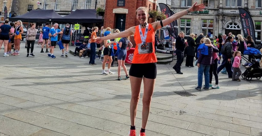 Runner proudly holding her Bangor 10K medal after finishing her first 10K